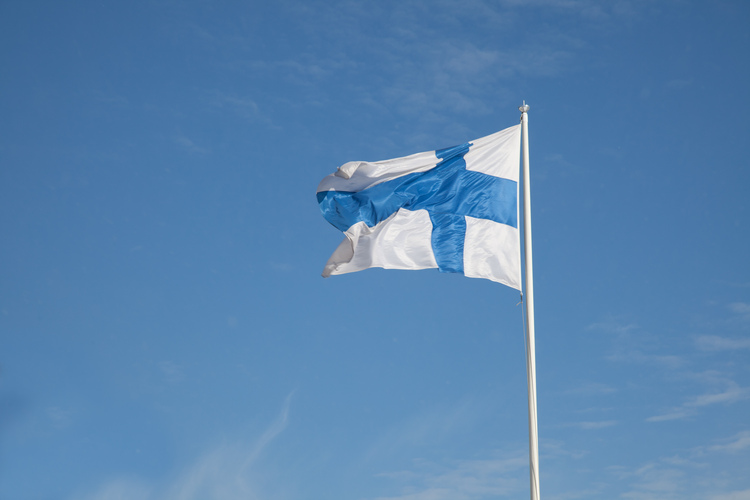 Finlands flagga som vajar med en blå himmel i bakgrunden.