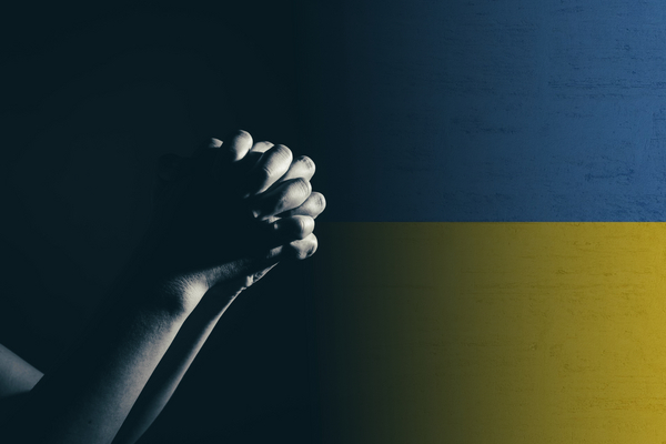 Knäppta händer i bön med Ukrainas färger blått och gult.