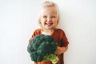 Barn med stor broccolibukett i handen.